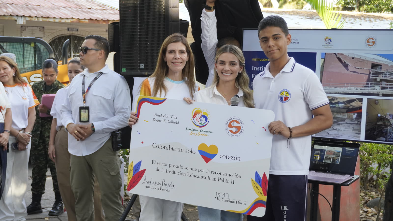 Ana Lucía Pineda y María Carolina Hoyos sostienen, junto a un estudiante, el cartel de la donación para la Institución Educativa Juan Pablo II